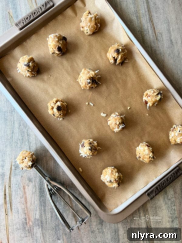Placing scoops of cookie dough onto a baking sheet lined with parchment paper.