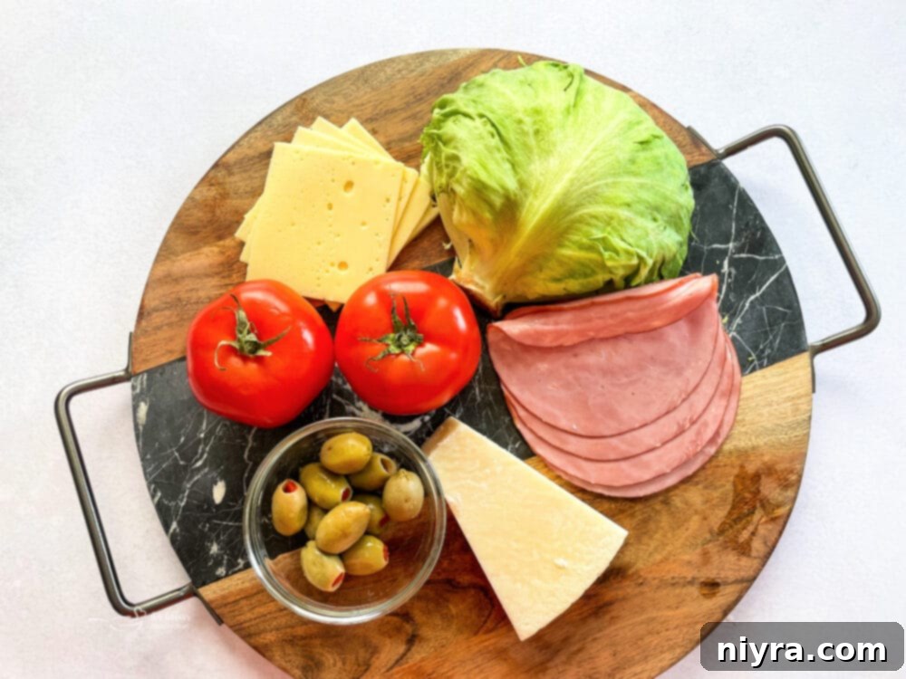 Raw ingredients for Columbia 1905 Salad: lettuce, tomatoes, ham, Swiss cheese, olives, and Romano cheese.