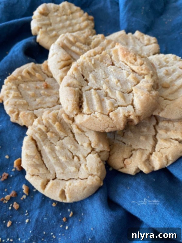 Top view of soft, golden brown peanut butter cookies arranged on a cooling rack, showcasing their classic criss-cross fork marks.