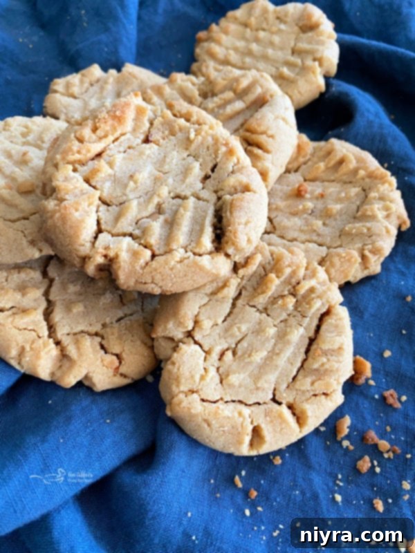 A stack of golden brown peanut butter cookies with prominent fork marks, emphasizing their delicious texture and homemade appeal.
