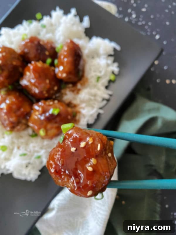 Sticky Asian Meatballs on rice with chopsticks holding one meatball