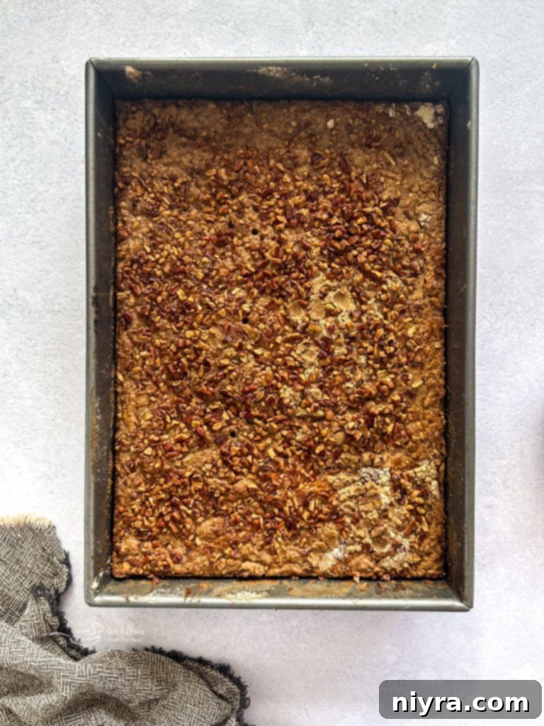 Dry cake mix and melted butter being layered over the pumpkin base in a baking dish