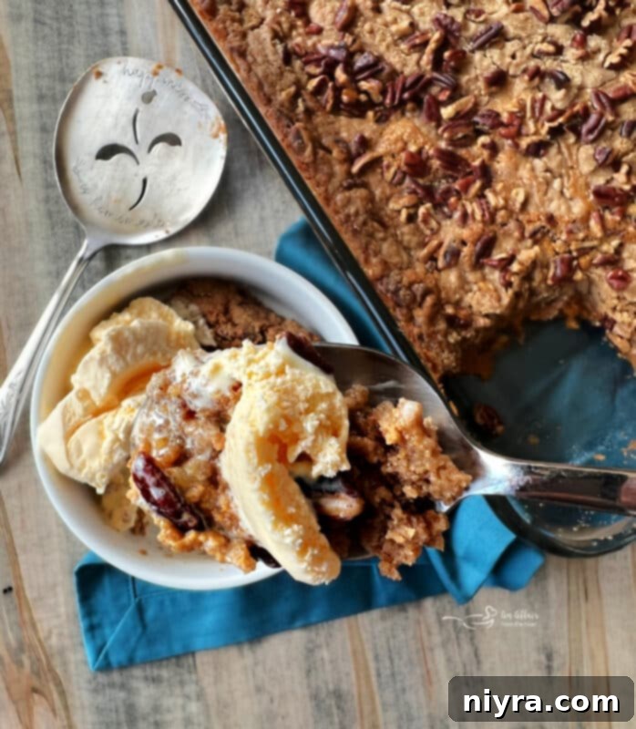 Close-up of a warm slice of Pumpkin Dump Cake with a scoop of vanilla ice cream