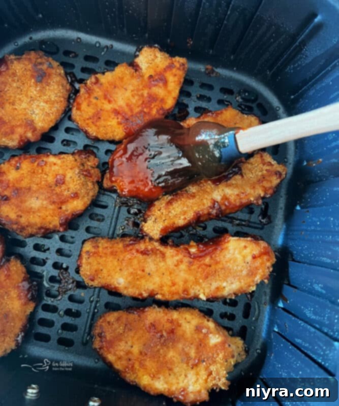 Crispy Air Fryer BBQ Tenders 11 Cooked chicken tenders being brushed with BBQ sauce