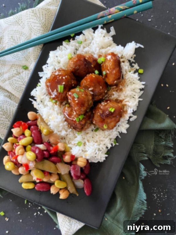 Crispy Air Fryer BBQ Tenders 17 Sticky Asian Meatballs on black plate over rice with bean salad
