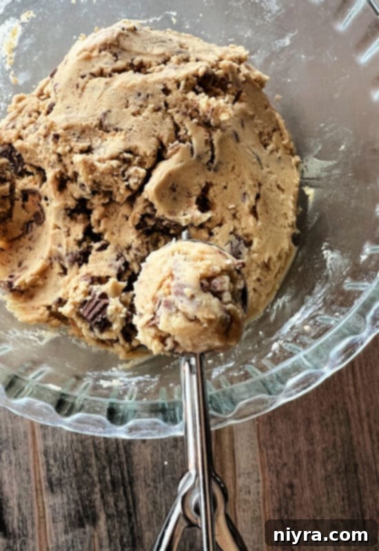 Reese's Peanut Butter Cup Minis being mixed into cookie dough.
