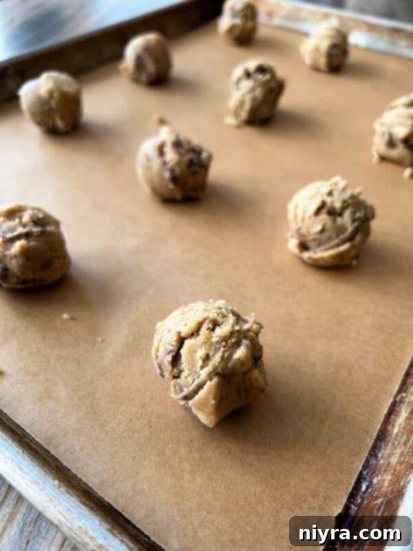 Scooping cookie dough onto a parchment-lined baking sheet.