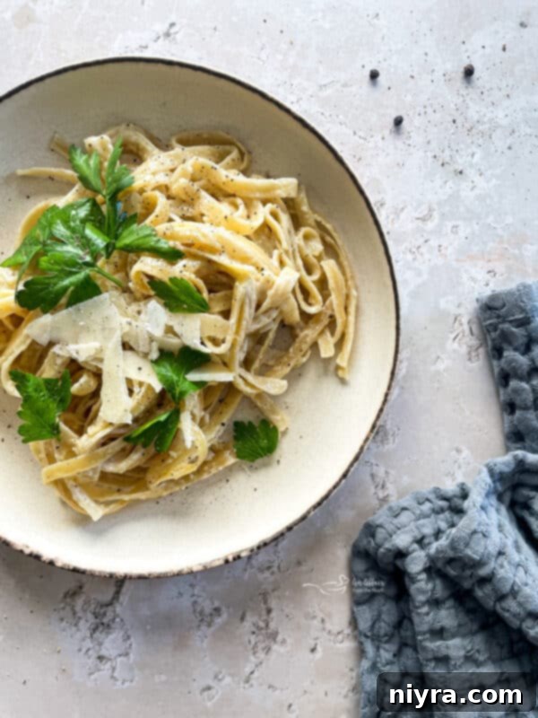 A close-up shot of creamy Instant Pot Fettuccine Alfredo in a serving bowl, garnished with fresh parsley.