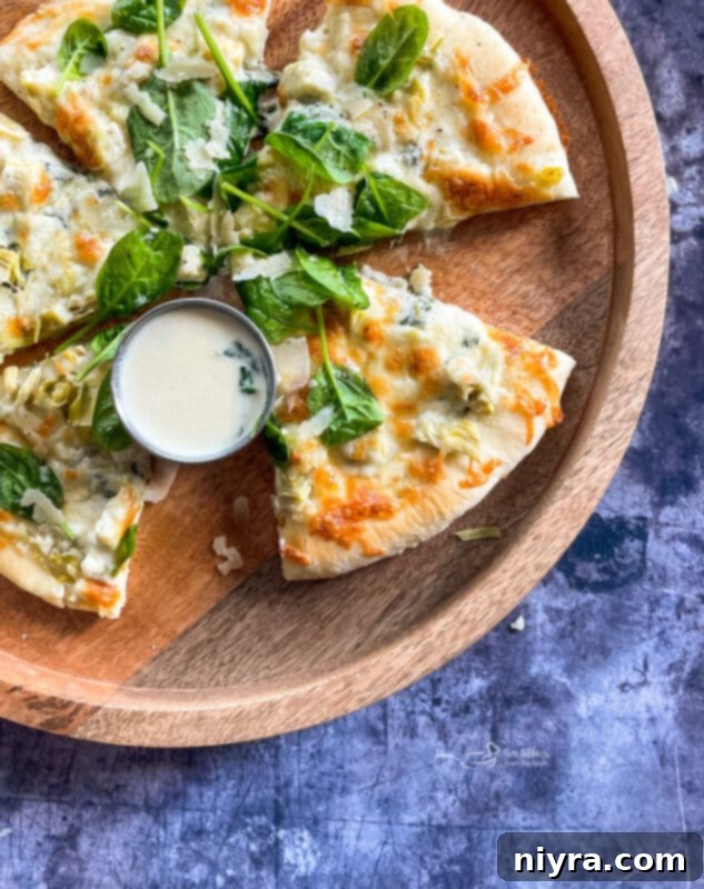 A delicious pizza topped with spinach and artichoke, showcasing a creamy Alfredo base.