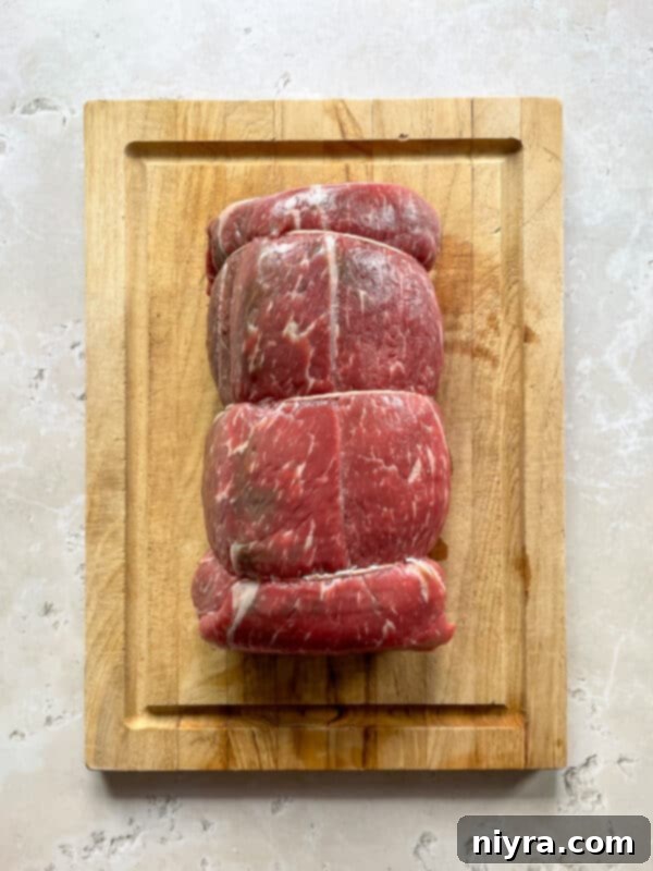 A seasoned chuck roast, tied with kitchen string, sits on a cutting board, ready for searing.