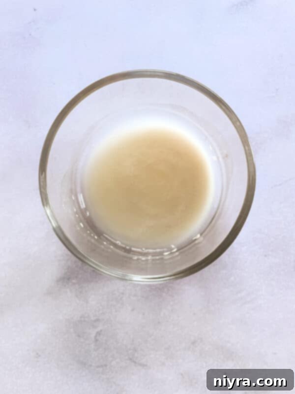 The initial mixing of water and flour in a large bowl, forming a shaggy dough.