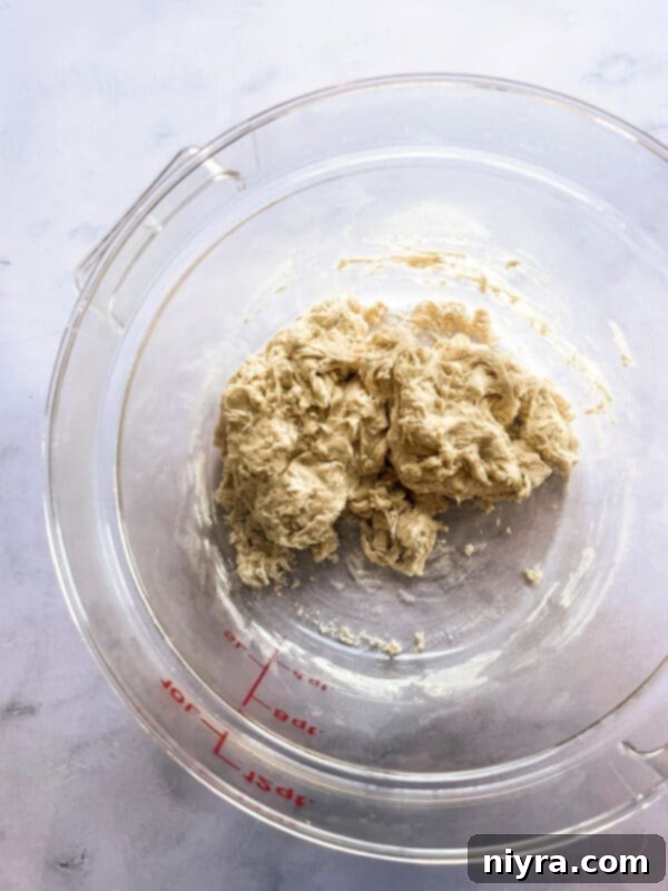 Close-up of activated yeast blooming in a small bowl with warm water.