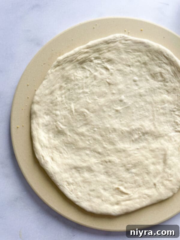A hand gently pressing into proofed pizza dough to test its readiness.