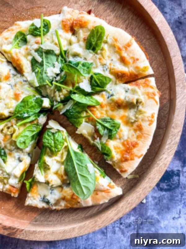 A delectable Spinach & Artichoke Alfredo Pizza, showcasing a golden homemade crust.