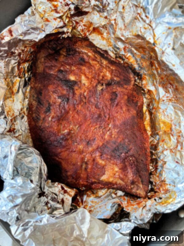 Spicy beef brisket cooking on a smoker, still wrapped in foil.