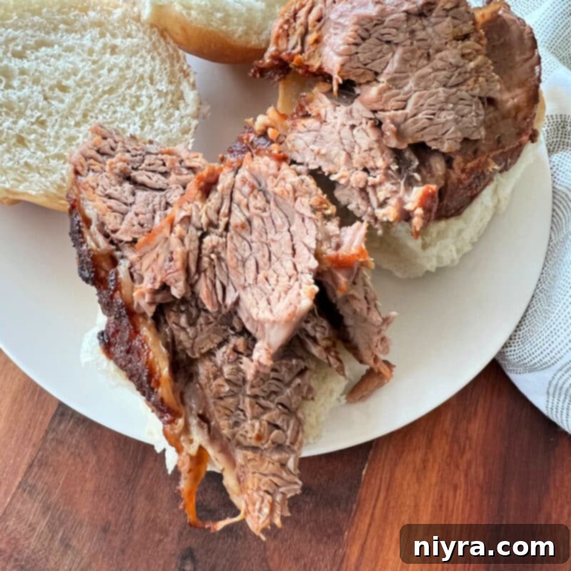Sliced spicy beef brisket being placed on a slider roll.