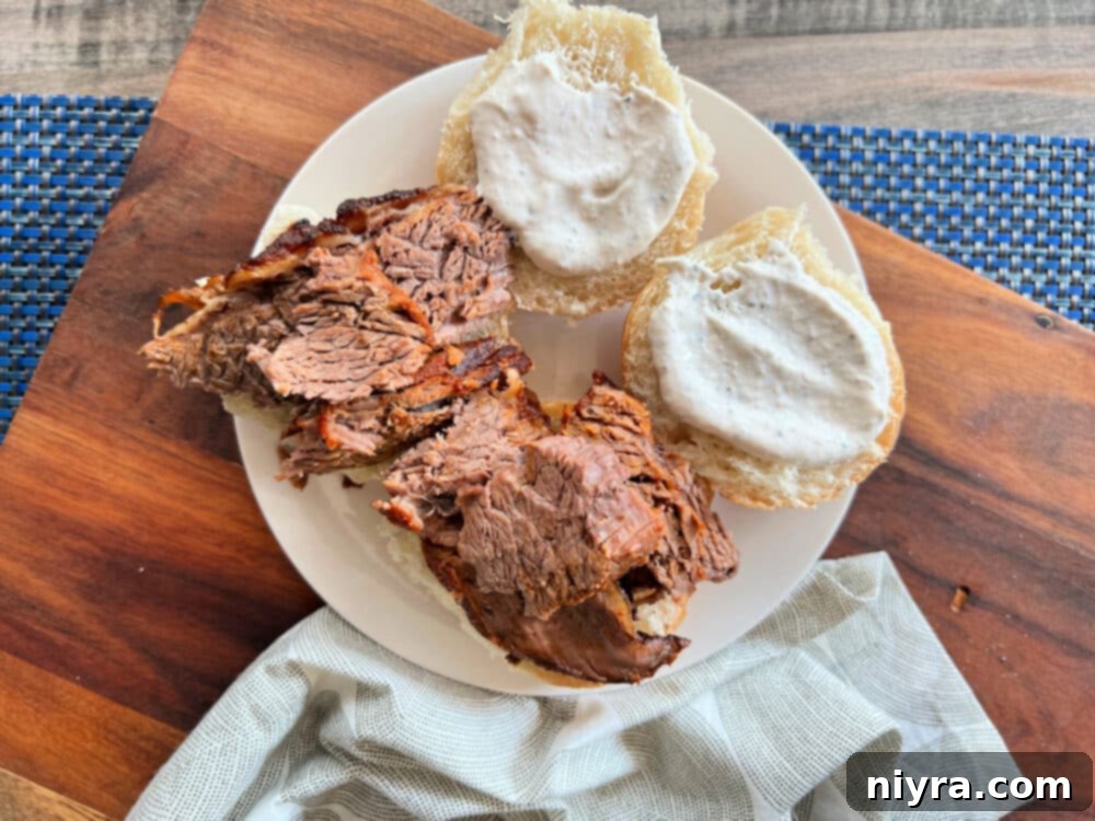 Homemade horseradish sauce being generously applied to a brisket slider.