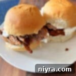 Two spicy beef sliders on a white plate.