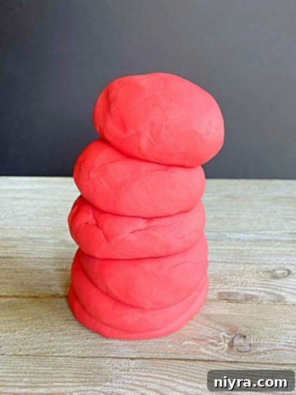 Stack of four different colors of homemade Kool-Aid playdough.