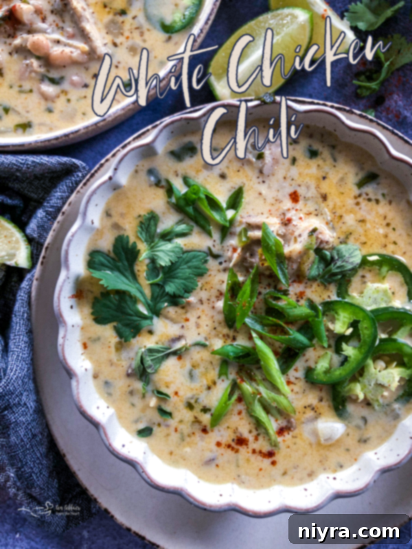A bowl of creamy White Chicken Chili garnished with fresh herbs and a spoon.
