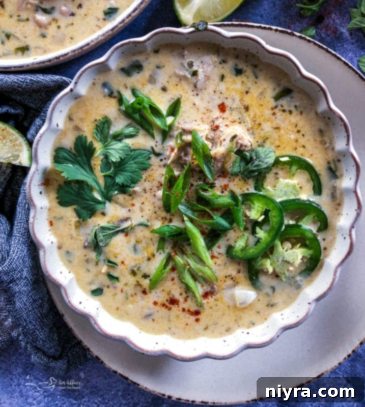 Close-up of a bowl of White Chicken Chili, garnished with fresh cilantro and a lime wedge.