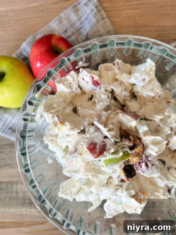 Close-up of Snicker Apple Salad in a large glass bowl, featuring diced apples, Cool Whip, and chopped Snickers candy bars.