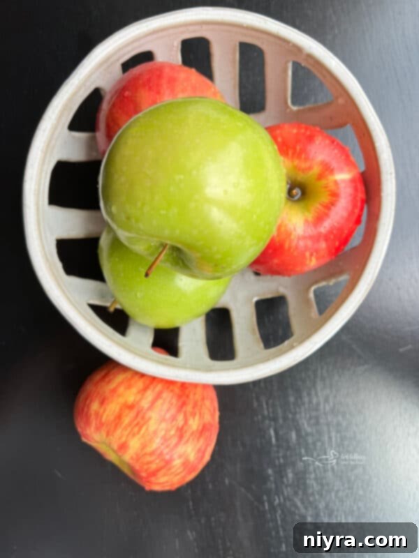 Overhead shot of diced apples, whole Snickers bars, and a tub of Cool Whip, ready for preparation of Snicker Apple Salad.