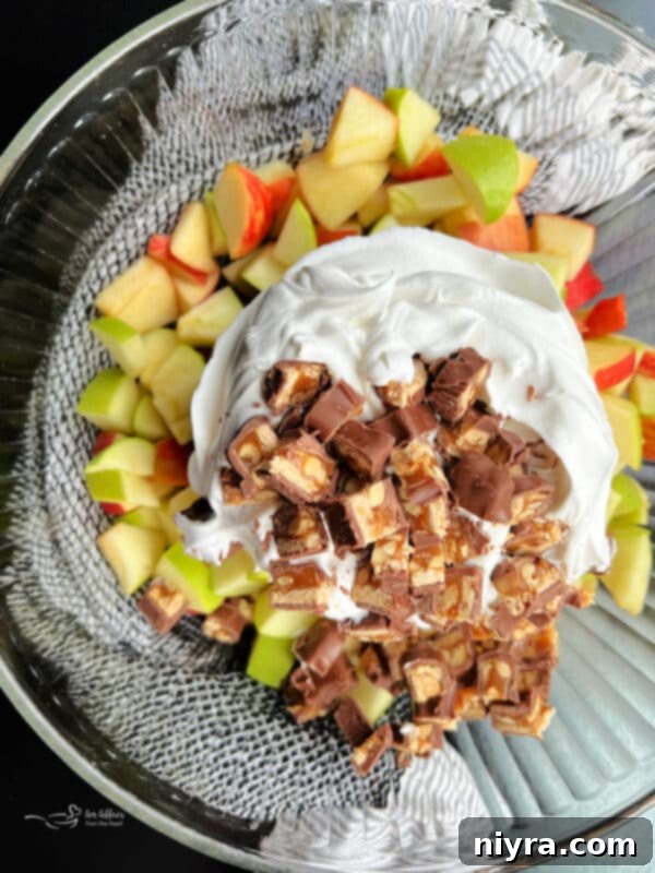 Image demonstrating the third step: combining apples, Snickers, and Cool Whip.