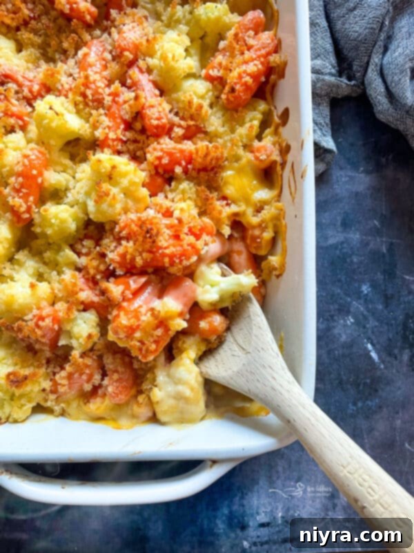 A vibrant cauliflower and carrot gratin in a white baking dish, ready to serve.