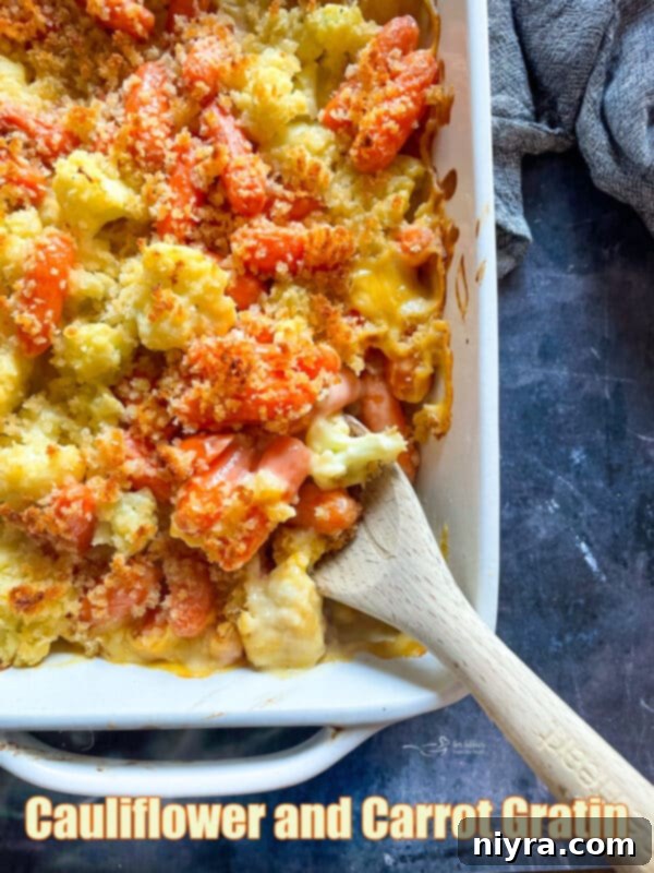 Cauliflower Carrot Gratin in a white baking dish with a wooden spoon.