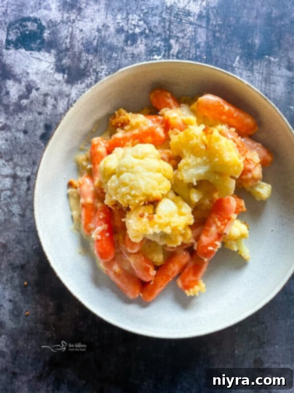 Scoop of creamy cauliflower and carrot gratin being served.