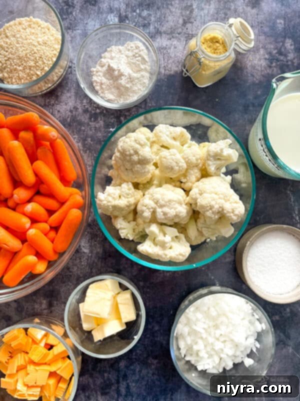 Top down view of ingredients for cauliflower carrot gratin on a white marble surface.