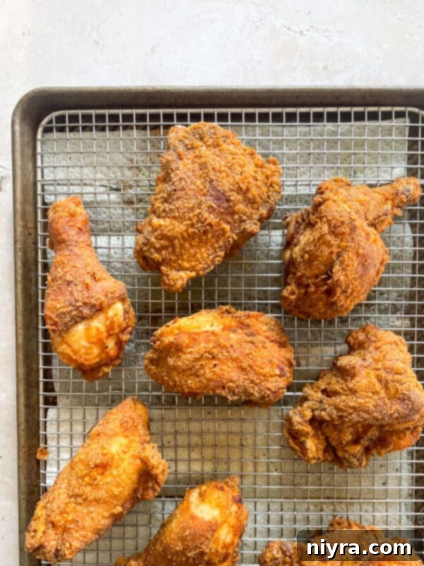 Crispy fried chicken pieces sizzling in hot oil in a cast iron skillet.