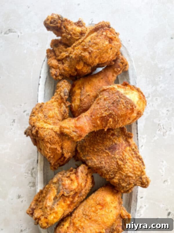 A plate piled high with golden brown, crispy fried chicken and a side of creamy coleslaw.