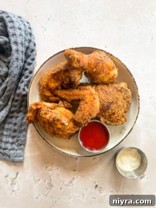 A single piece of golden brown, crispy fried chicken resting on a wooden cutting board.