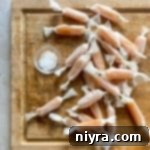 Wrapped homemade caramels on a wood cutting board.