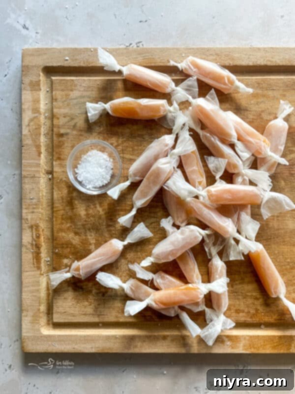 Cooled caramel being cut into squares on a cutting board.