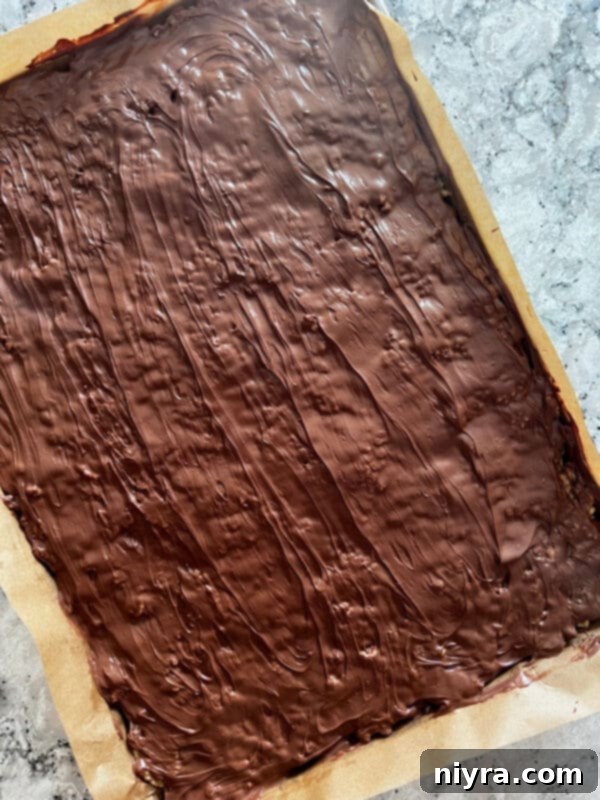 Pouring melted chocolate and butterscotch over the cereal base.
