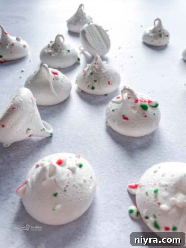 Minty Dream Clouds 12 A festive close-up of peppermint meringues with subtle holiday decorations in the background.
