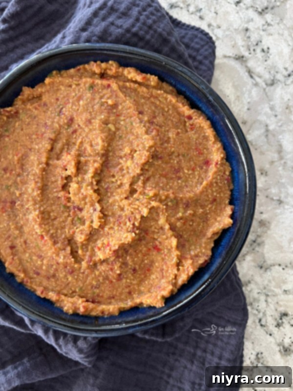 Step 3: The finished Asian Bean Dip is spread smoothly into a decorative serving dish and elegantly garnished with fresh green onions and toasted sesame seeds, ready to be served.