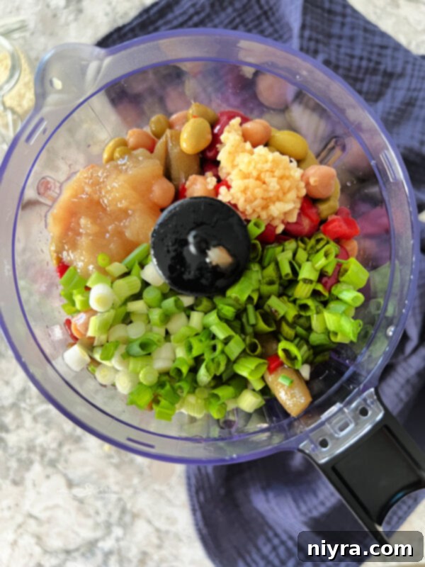 Step 1: All ingredients for the Asian Bean Dip, except garnishes, are placed into the bowl of a food processor, ready for blending.