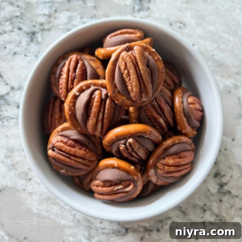 A festive holiday tray featuring an assortment of Rolo Pretzel Bites with various M&M colors and other holiday treats.