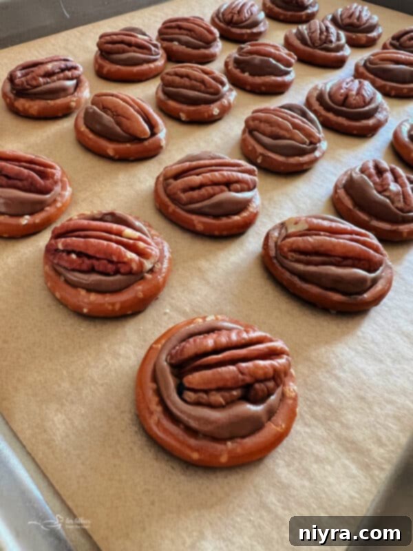 Rolo candies placed on top of circular pretzels on a baking sheet, ready for the oven.