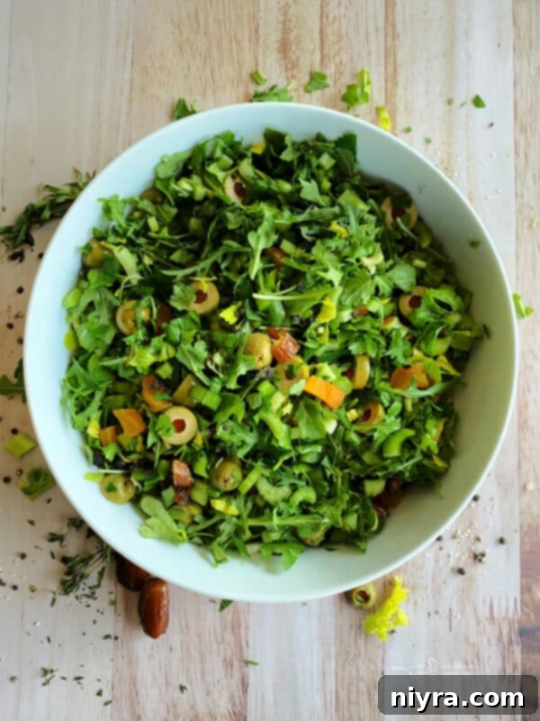 Bright Mediterranean Celery Olive Salad 10 Step 3: Olives, dried apricots, and dates are added to the bowl of greens.