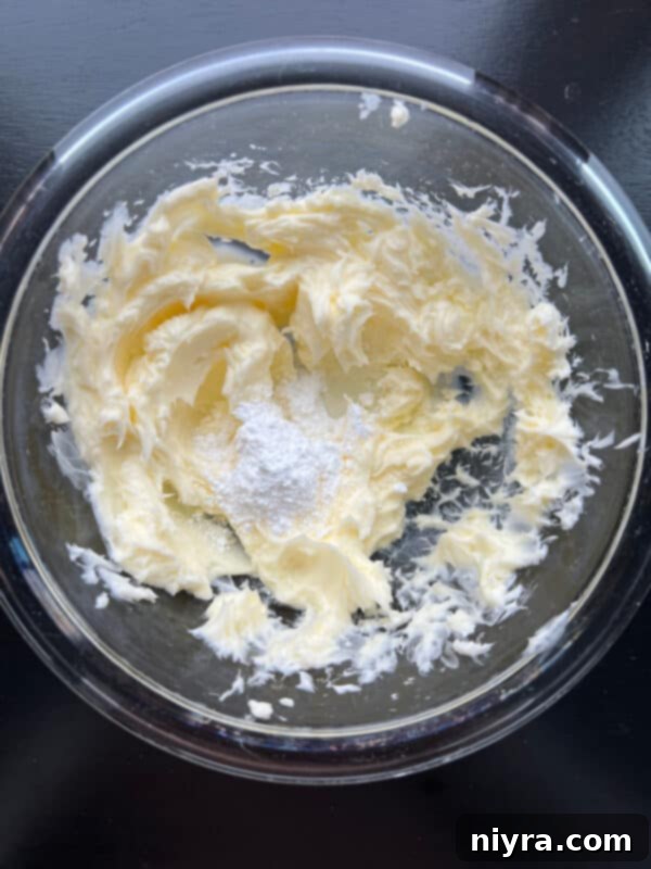 Crimson Cherry Whip 7 Step 2: Adding almond extract and powdered sugar to the creamed butter.