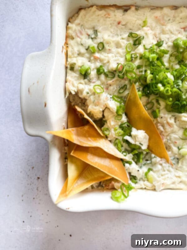 Warm Crab Rangoon Dip in a white baking dish, surrounded by crispy wonton chips.
