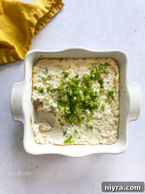 A baking dish filled with creamy Crab Rangoon Dip, freshly baked and garnished, ready to be served.