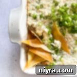 Close up of Crab Rangoon Dip with wonton chips in a white baking dish.