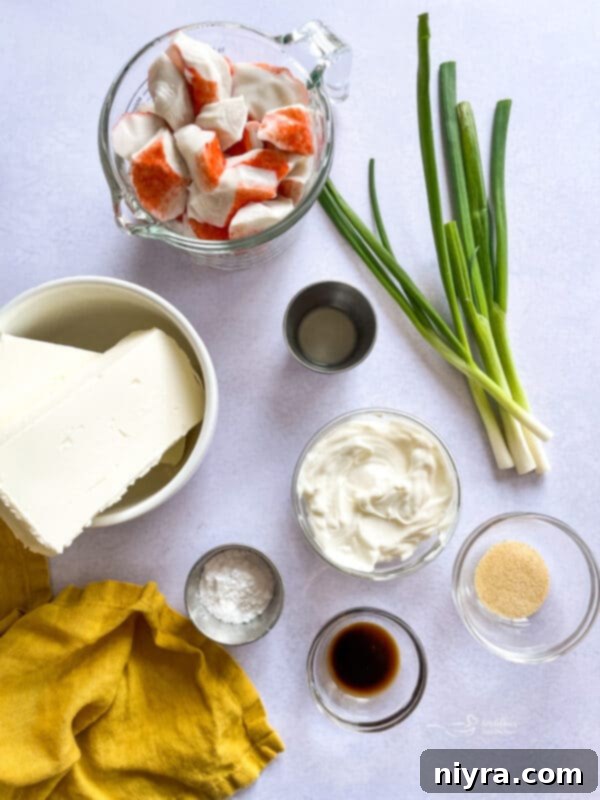 Ingredients for Crab Rangoon Dip laid out on a kitchen counter, including crab meat, cream cheese, and green onions.