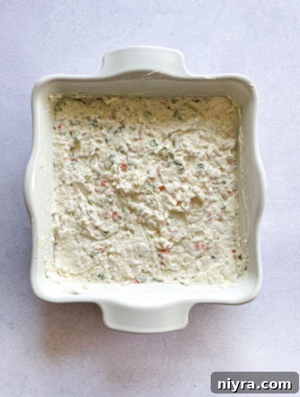 Crab meat and chopped green onions being folded into the creamy dip mixture in a bowl.
